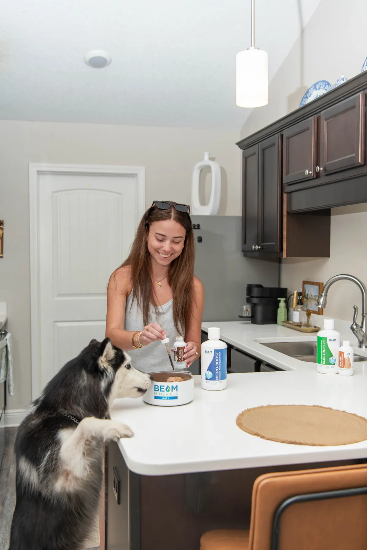 A woman adding BEAM Minerals to her dog's bowl in the kitchen