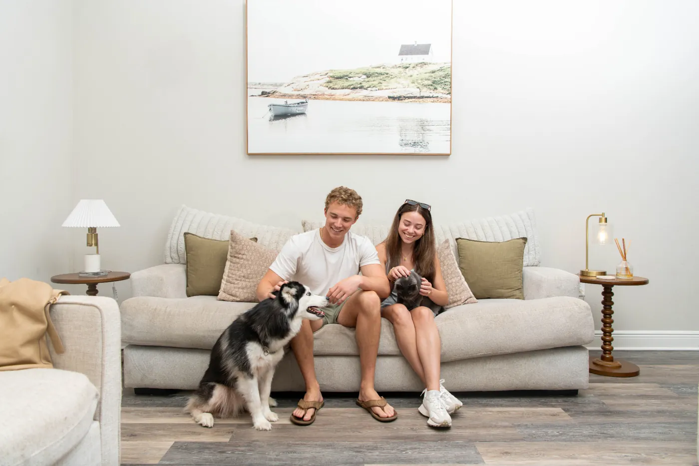 A couple on a couch with their dog and cat