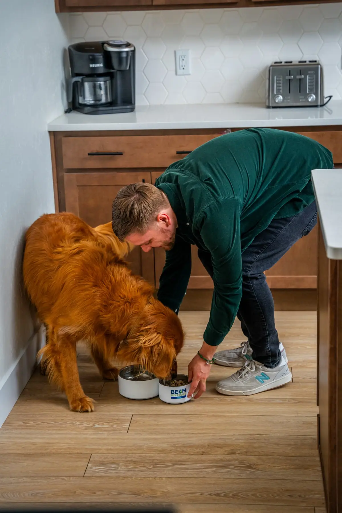 Pet parent adding BEAM Minerals to a golden retriever's bowl in the kitchen